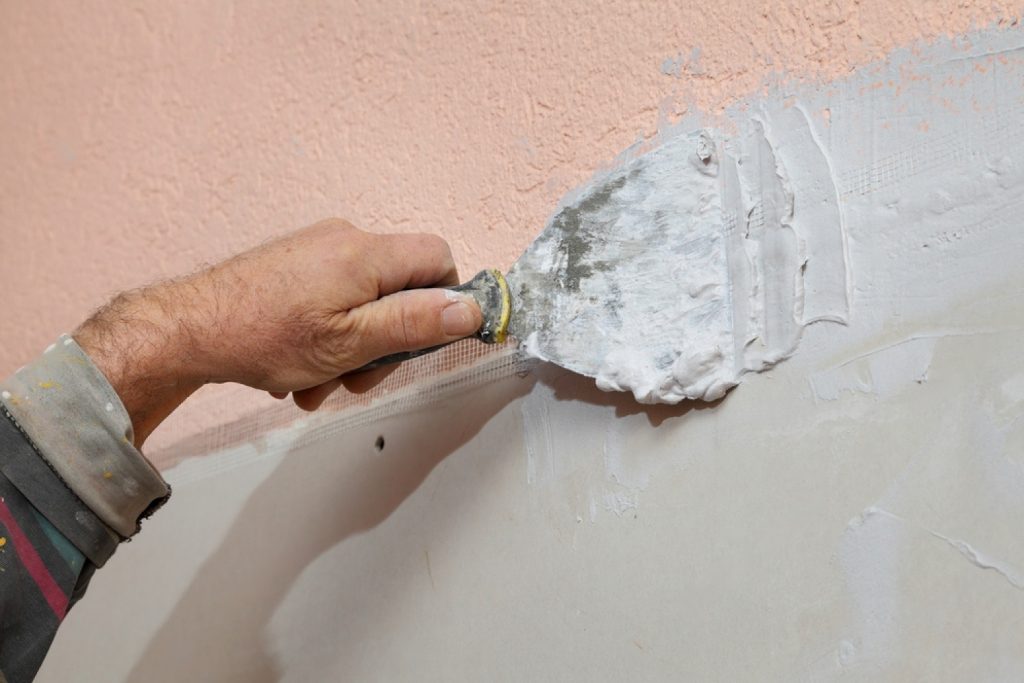 stock-photo-worker-spreading-plaster-with-trowel-to-gypsum-board-and-fiber-mesh-162598424-transformed